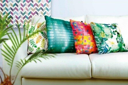 Printing technology which has been used to create bright textiles for cushions placed on a sofa.