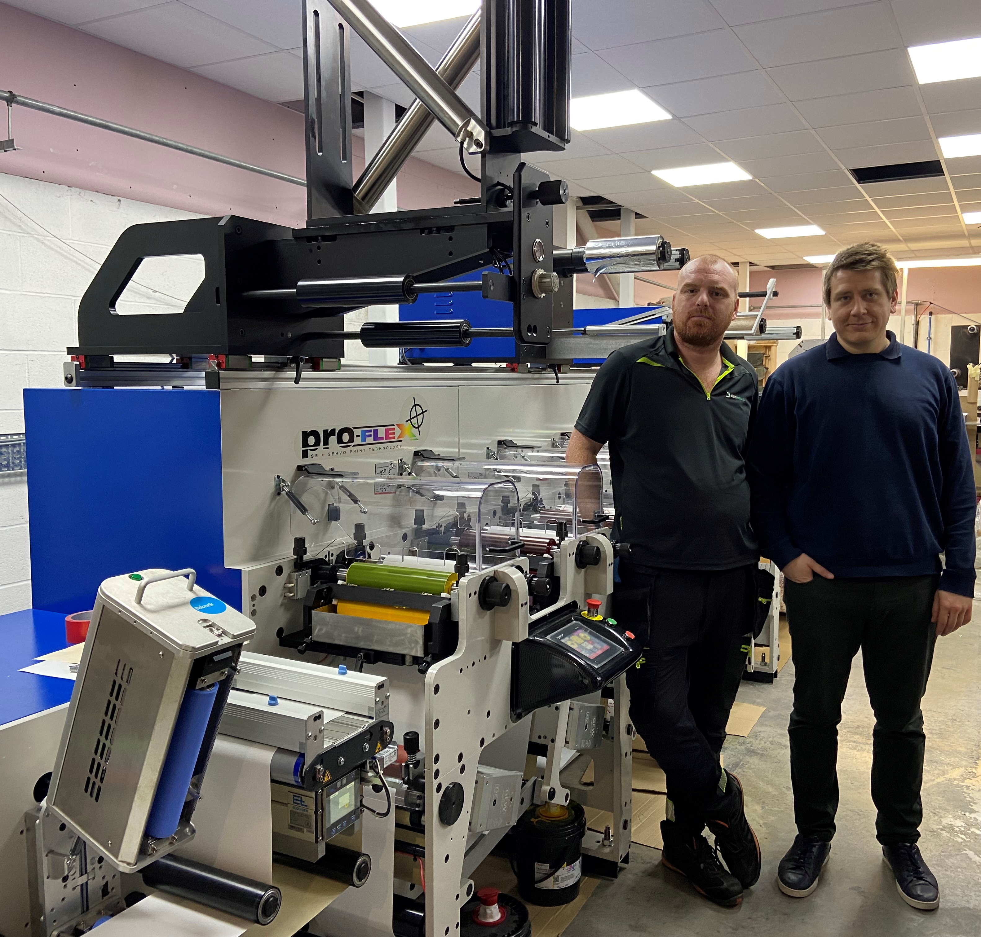Two men stood proudly next to the newly installed Proflex SE printer at DATAMARK.